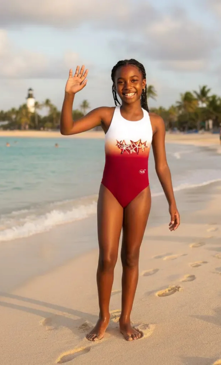 Seastars girls one-piece swimsuit with red and white starfish print, model on beach, made in Canada